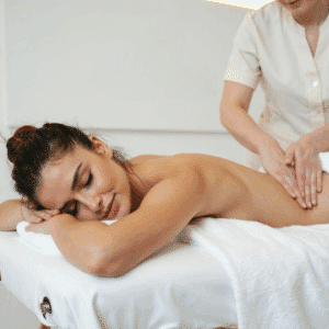 Persona recibiendo un masaje relajante en casa, con luz tenue, aceites esenciales y ambiente tranquilo. Refleja bienestar, paz y atención personalizada en el Valle del Tiétar.