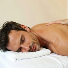 Hombre disfrutando de un masaje relajante a domicilio en su casa, con ambiente tranquilo y profesional.